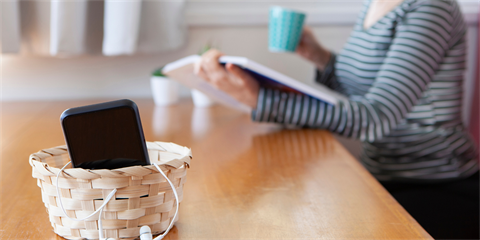 Smartphone inside a basket with person reading in the background.