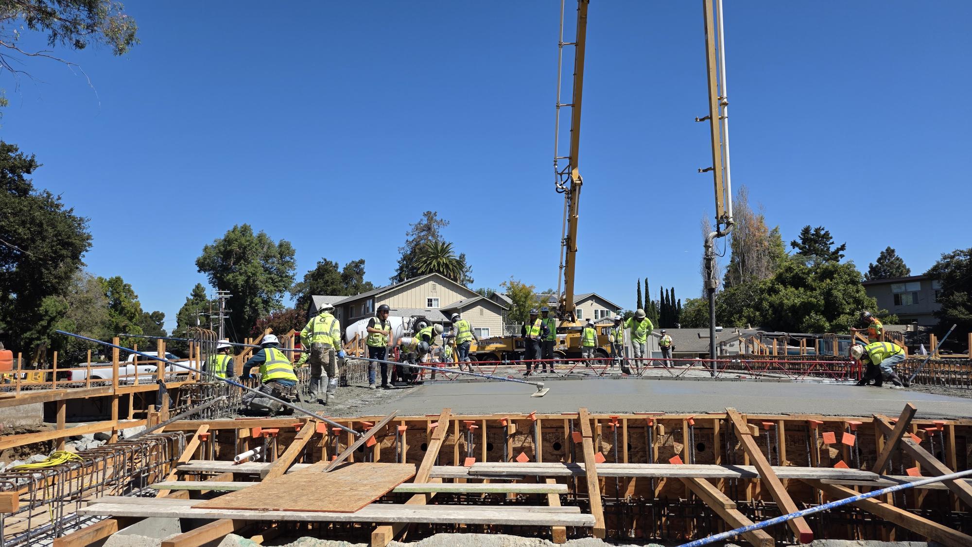 Construction crew pouring and leveling wet concrete