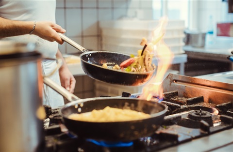 chef pan-frying vegetables in oil
