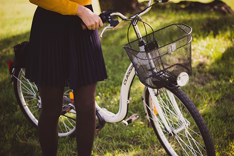 A person wearing a skirt walks their bike
