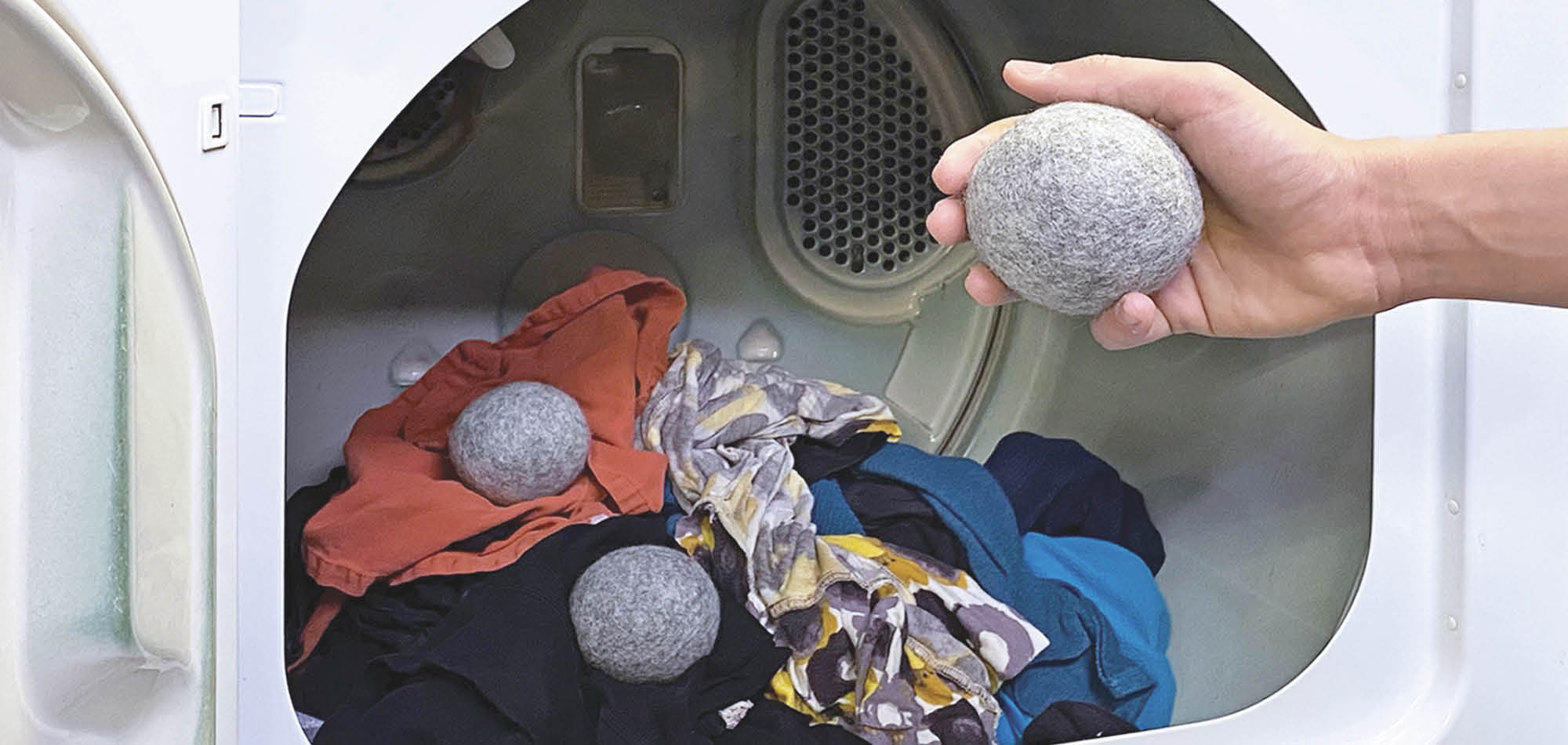 Person putting Wool Dryer Ball into dryer