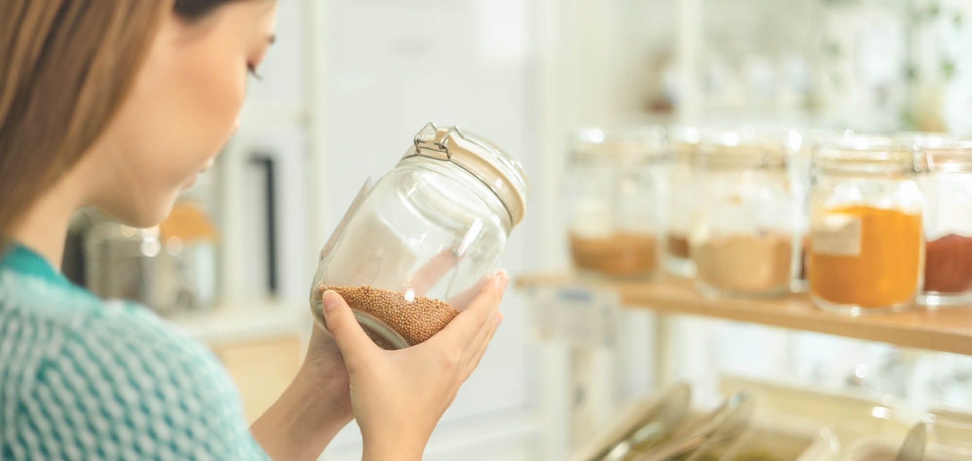 woman filling mason jar from a Bulk Bin