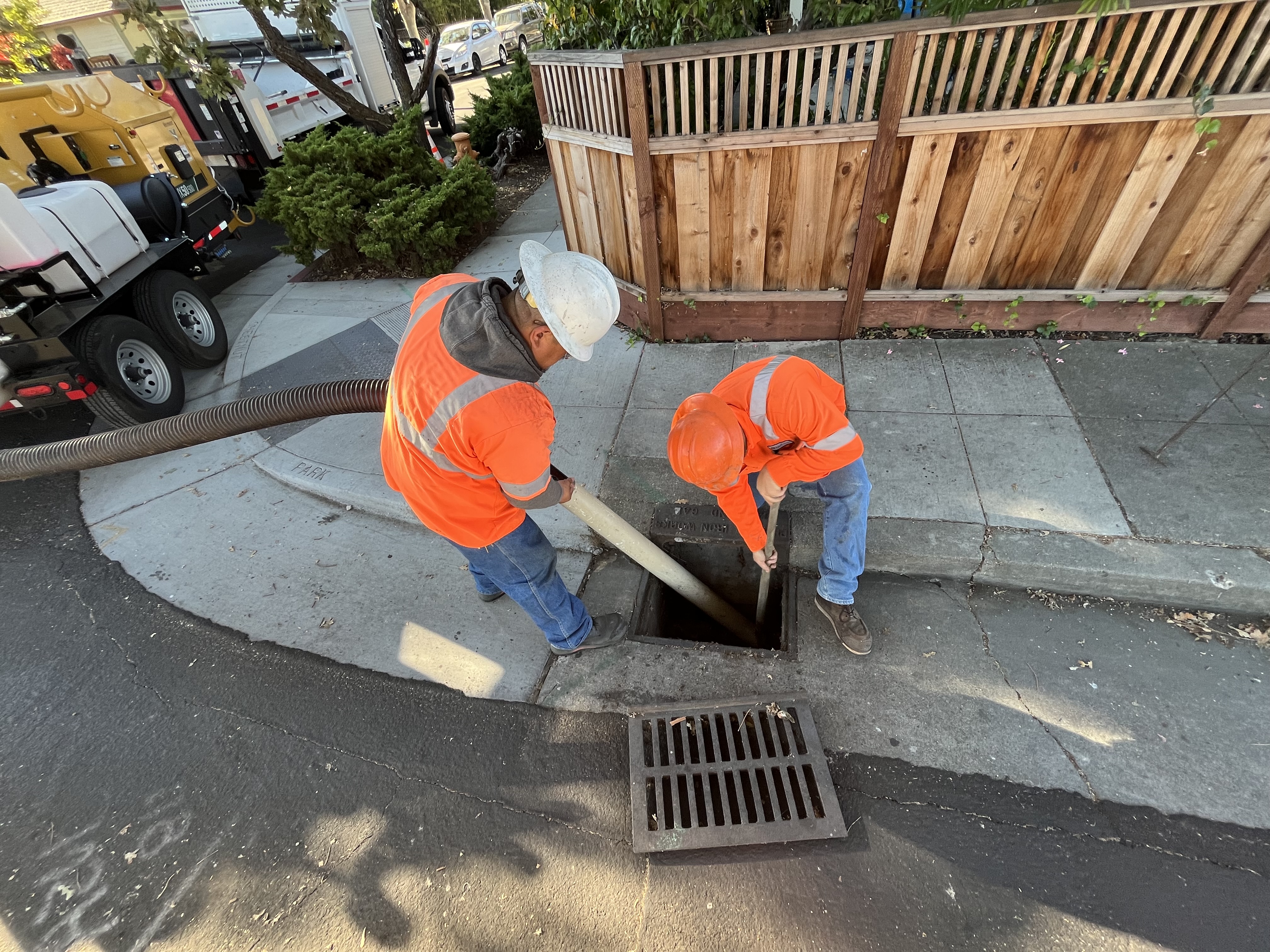 Public service staff cleaning out storm drain.