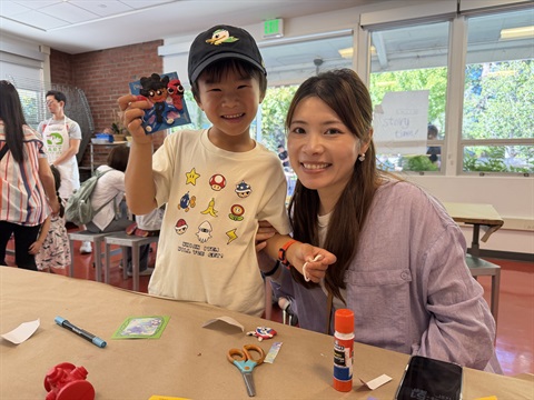 image of a child holding up artwork with a caregiver