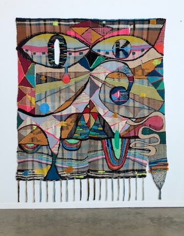 textile hanging from wall with bright colors and a variety of shapes
